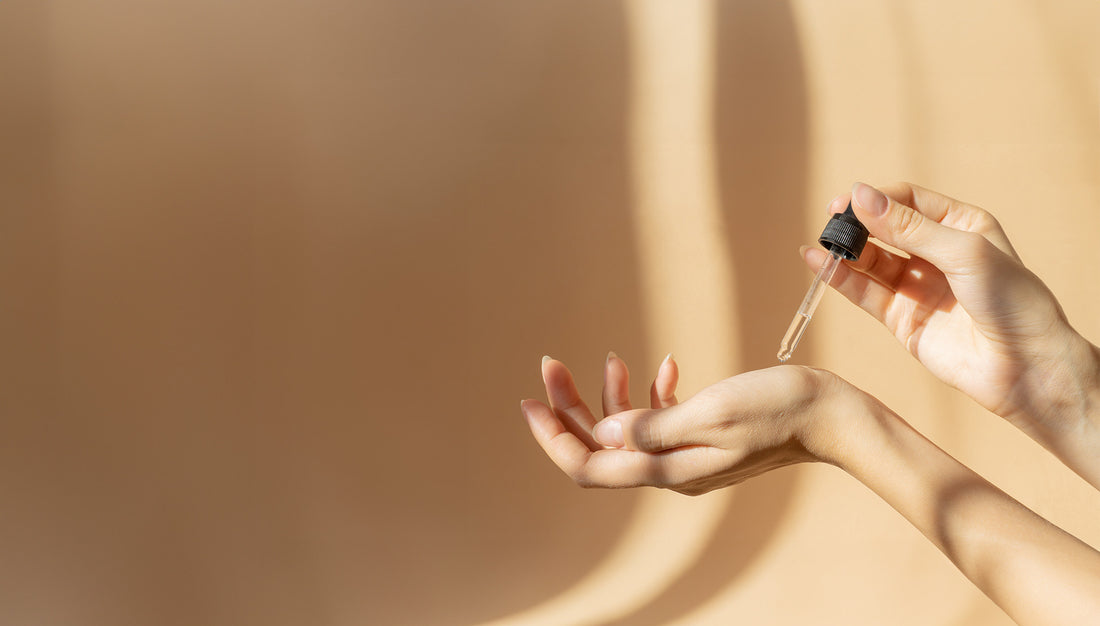 Close-up on a Sym Biologic System pipette precisely depositing drops of product on a hand, representing targeted anti-aging care for hands.